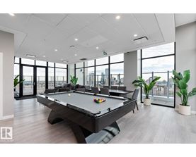 A spacious room with grey carpeting and a view of the street through the windows.