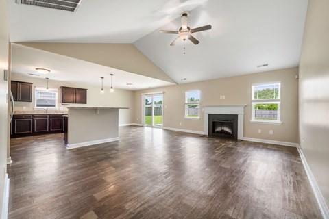 A spacious living room with wood flooring and a ceiling fan.