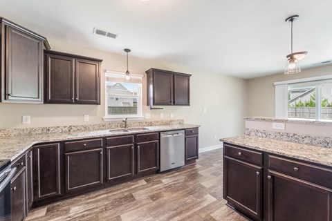 A kitchen with dark brown cabinets and a granite countertop.