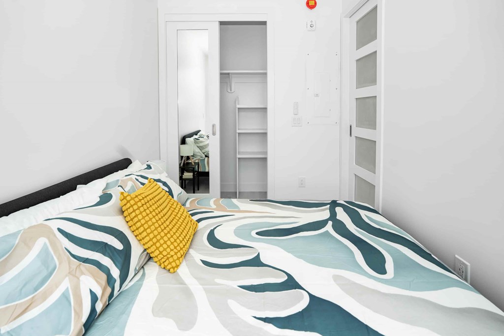 A bed with a yellow pillow and a blue and white comforter.