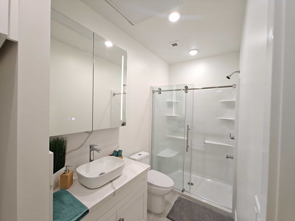 A white bathroom with a sink, toilet, and shower.