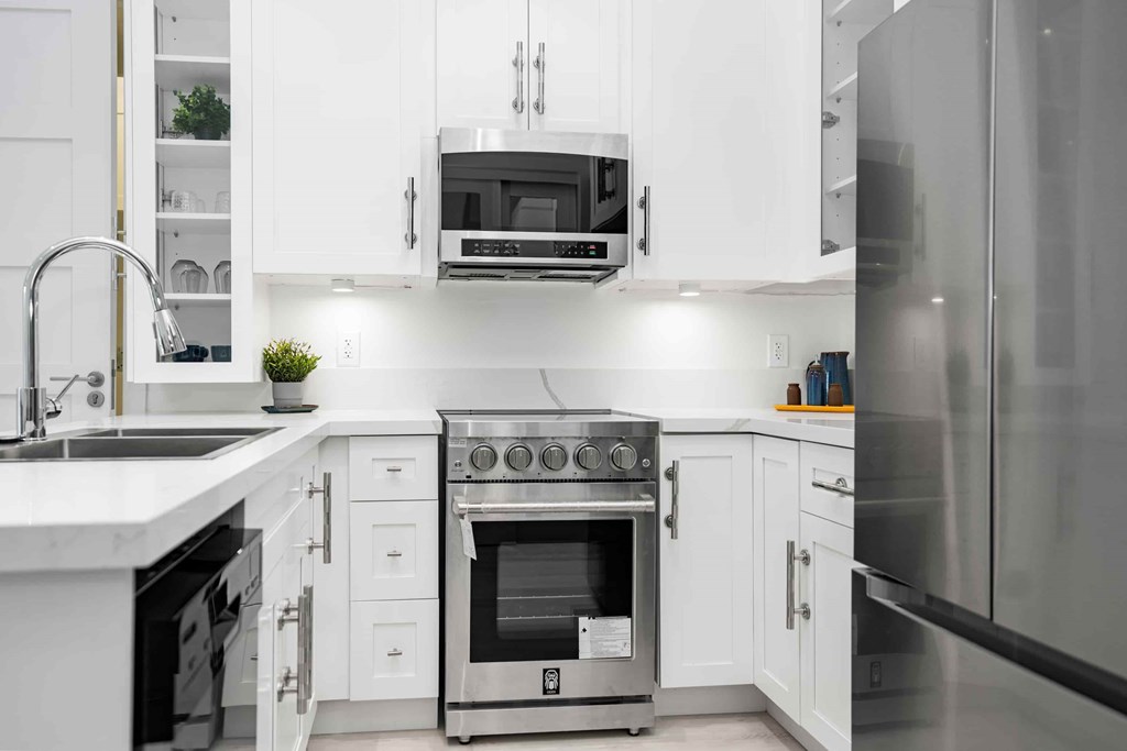 A modern kitchen with white cabinets and stainless steel appliances.