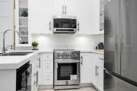 A modern kitchen with white cabinets and stainless steel appliances.