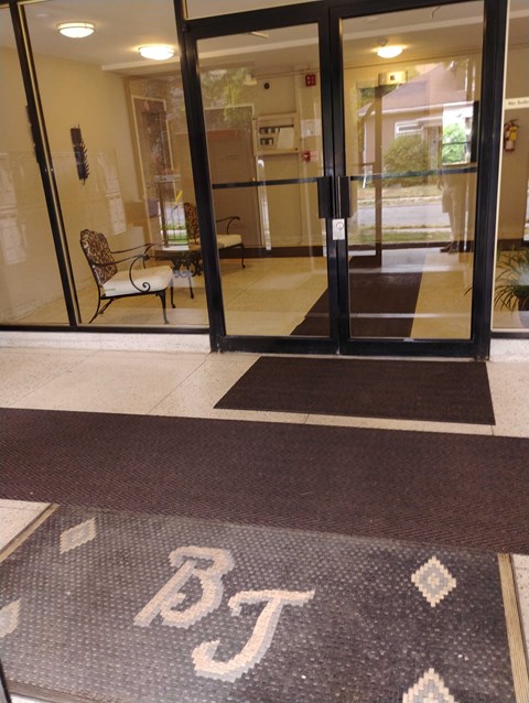A glass door with a mat in front of it that says BT.