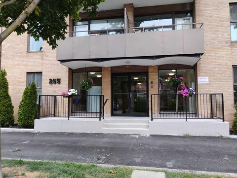 A building with a balcony and a sign that reads "245" on the front door.