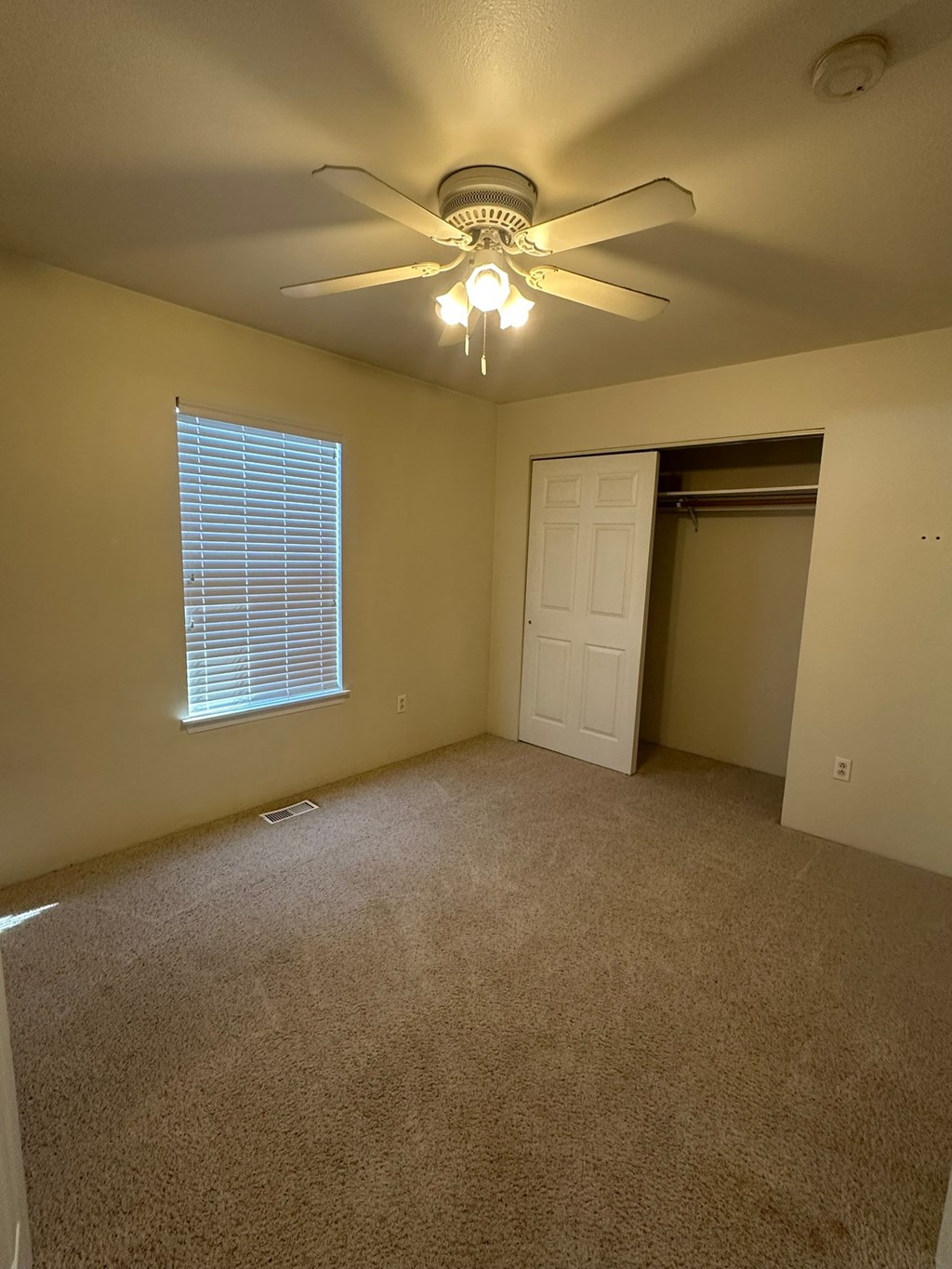 A room with a ceiling fan and a window with blinds.