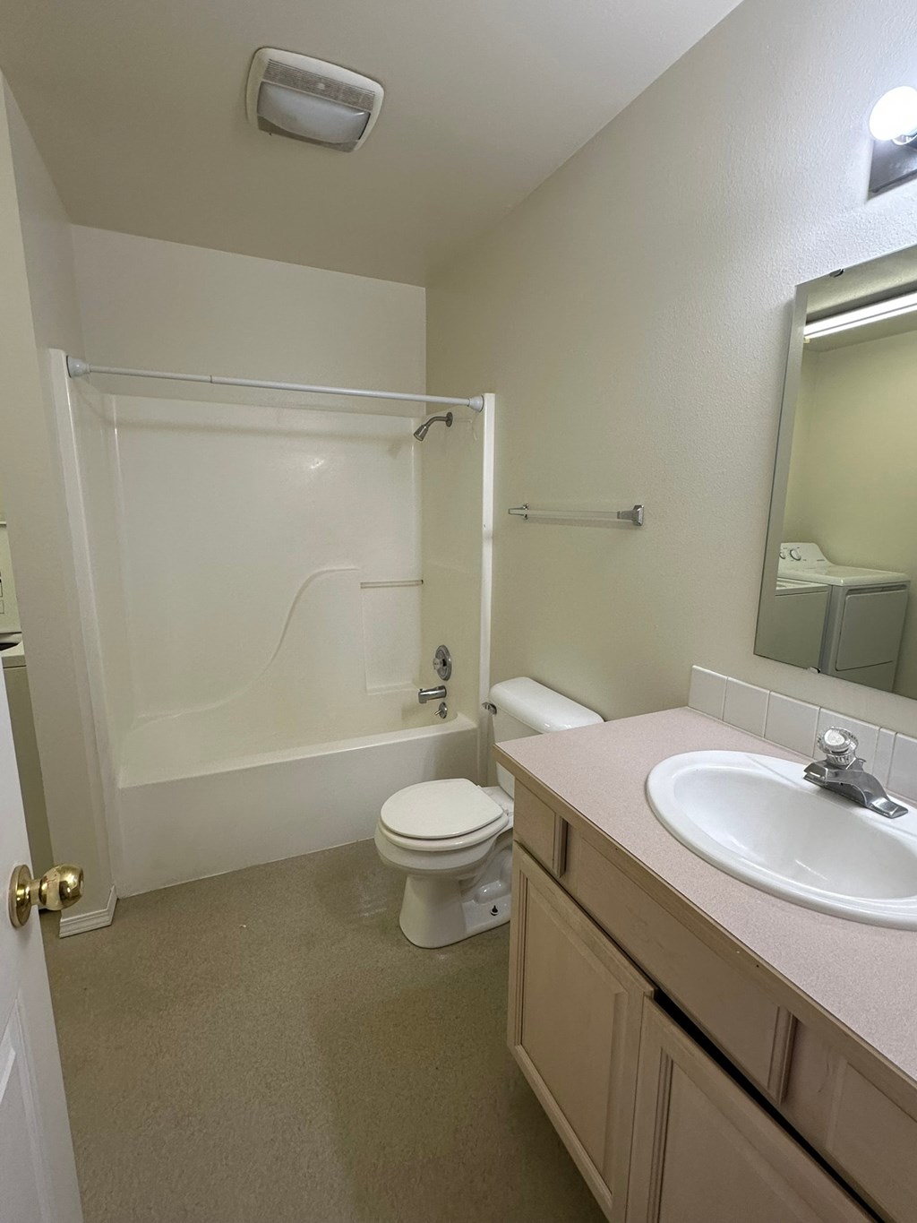 A white toilet is in a bathroom with a sink and mirror.