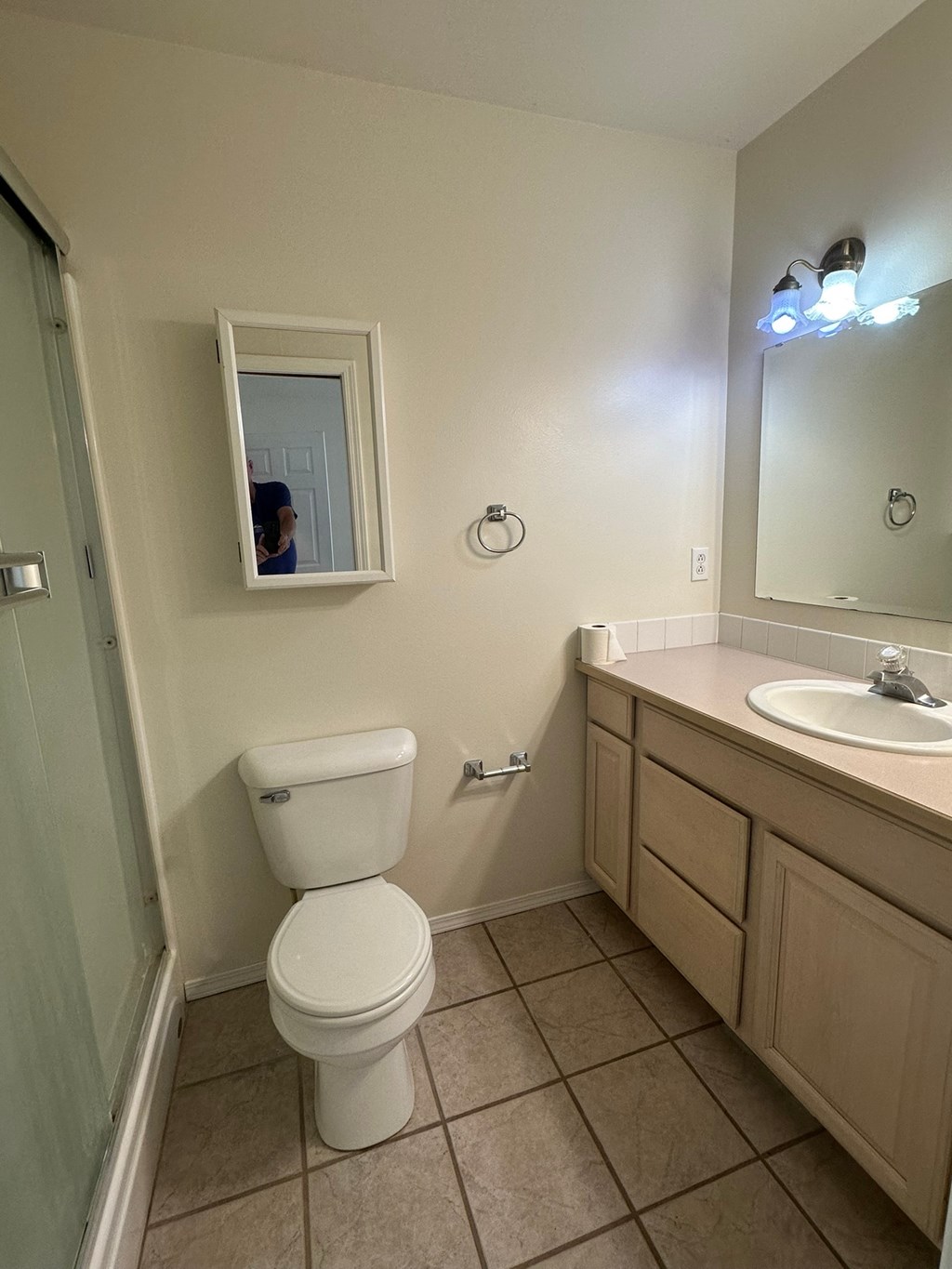 A white toilet in a bathroom with a mirror and sink.