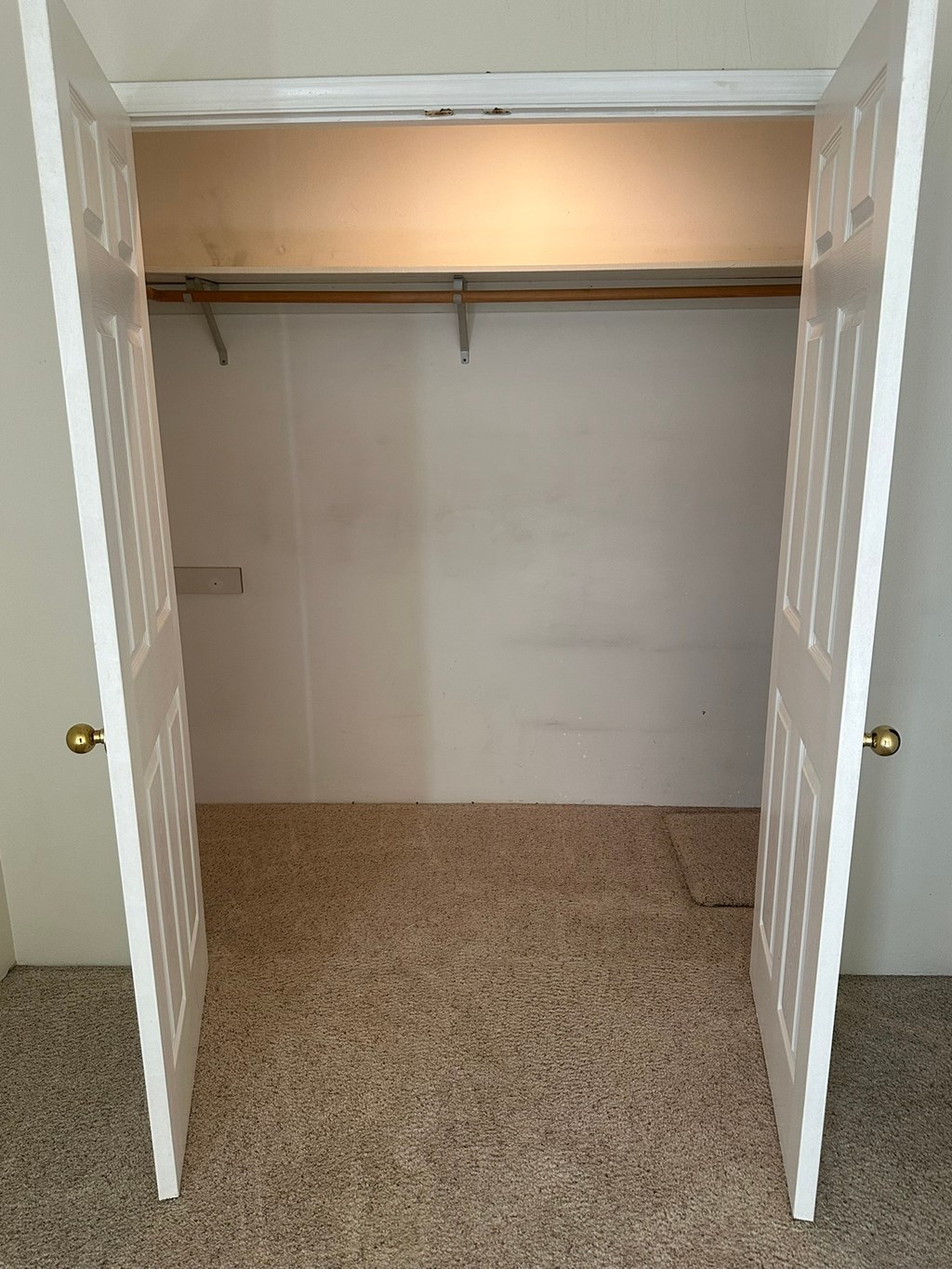 A white door is open to a small, empty room with a carpeted floor.