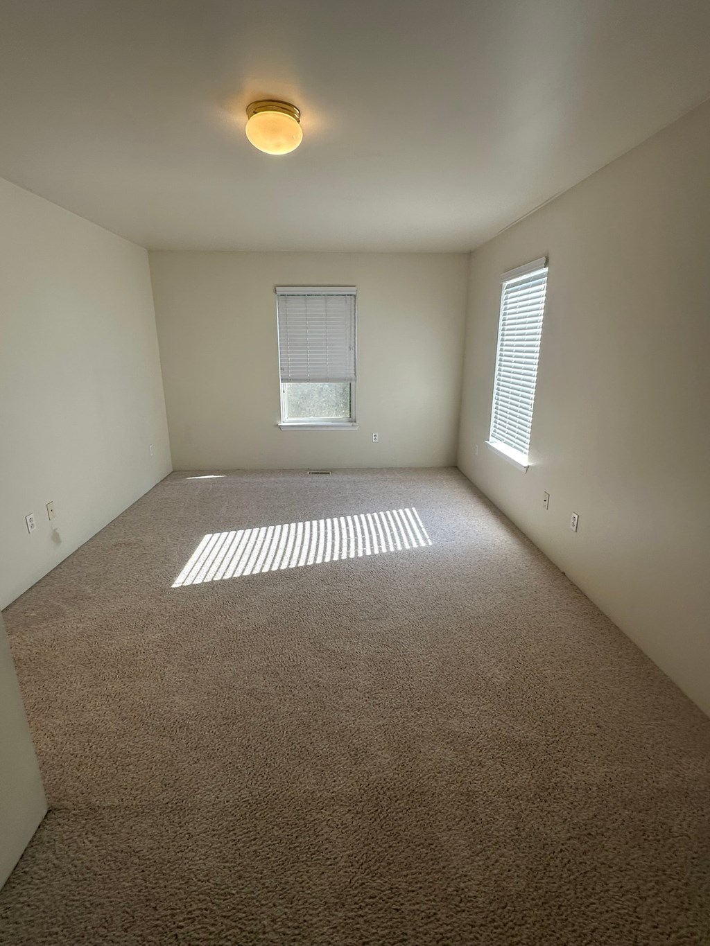 A room with a carpeted floor and a window with blinds.
