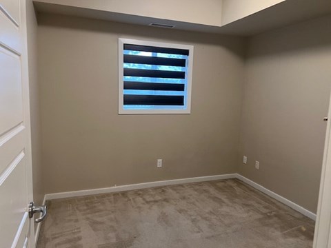 A room with a window and carpeted floor.