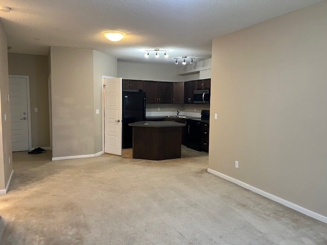 A kitchen area with a black refrigerator and microwave.