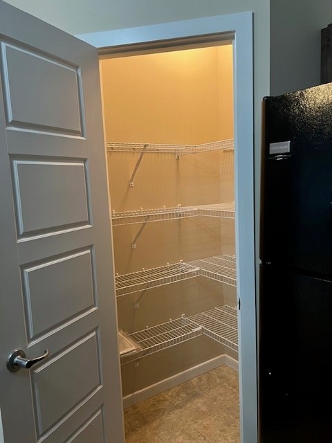A black refrigerator is to the right of an open white door.