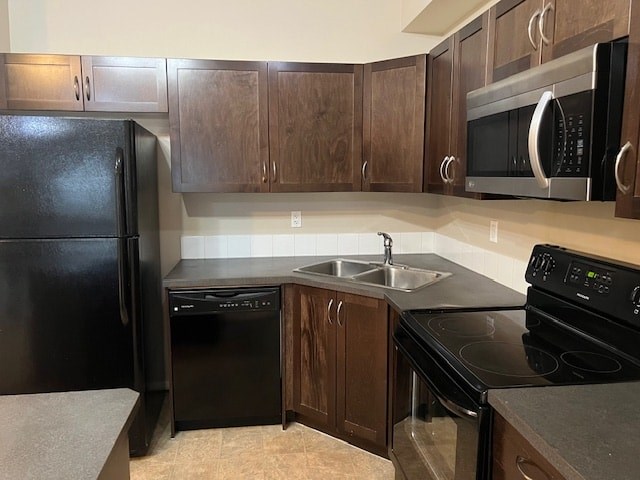 A black refrigerator is in a kitchen with brown cabinets.