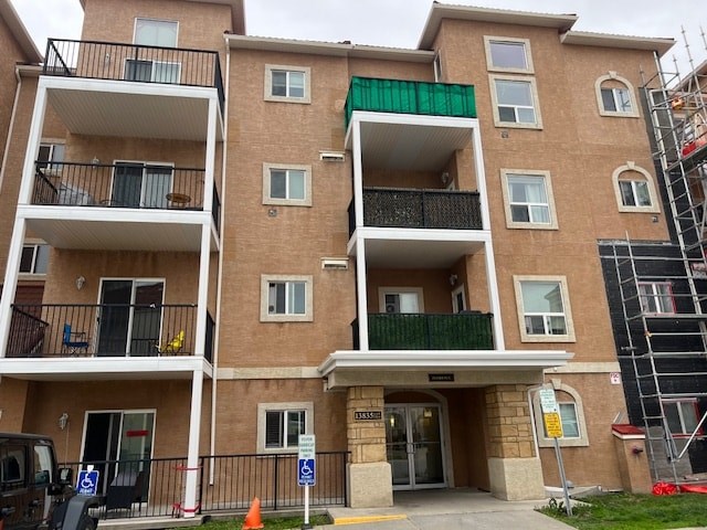 A multi-story apartment building with a green awning and a sign that reads "Parking.".