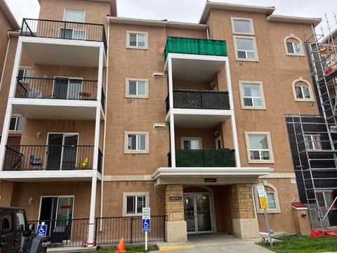 A multi-story apartment building with a green awning and a sign that reads "Parking.".