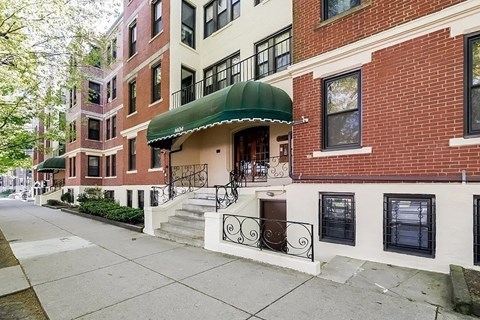 A row of red brick buildings with a green awning on the first one.