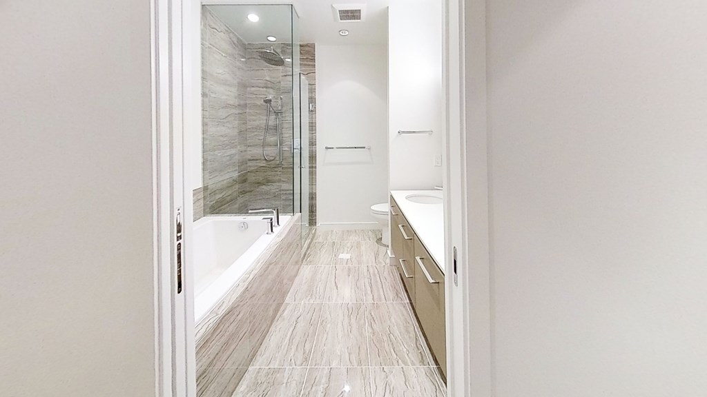 A bathroom with a walk-in shower and a white wall.