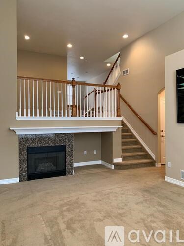 A living room with a fireplace and a staircase.
