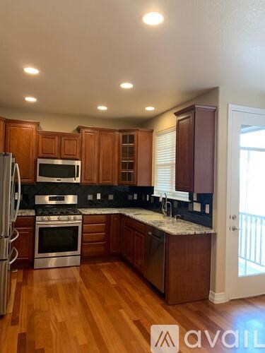 A kitchen with wooden cabinets and a stainless steel refrigerator.