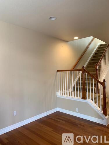 A wooden staircase with a white railing leads up to a lighted landing.