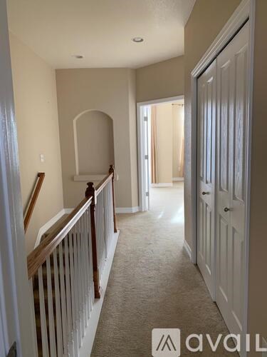 A hallway with a carpeted floor and a wooden railing.