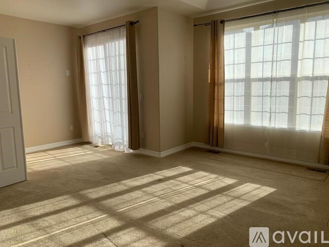 A room with a carpeted floor and a large window with curtains.