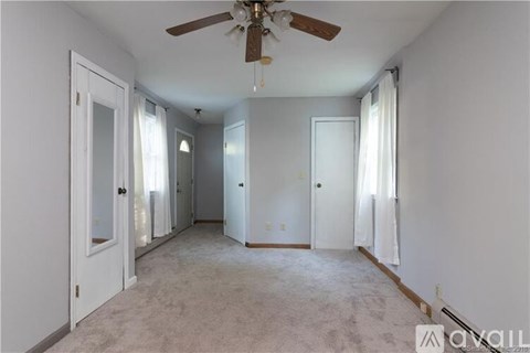 A spacious room with a ceiling fan and carpeted floor.