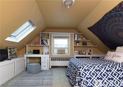 A bedroom with a bed, desk, and bookshelf.