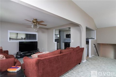 A living room with a red couch and a ceiling fan.