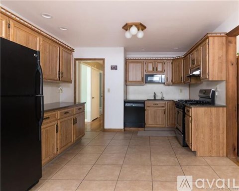 A kitchen with wooden cabinets and black appliances.
