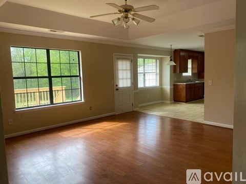 A spacious room with a ceiling fan and wooden flooring.