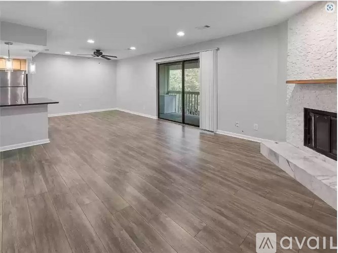A spacious living room with wood flooring and a fireplace.