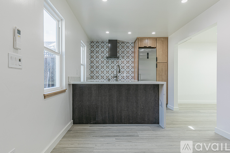A modern kitchen with a wooden cabinet and a black and white tiled backsplash.
