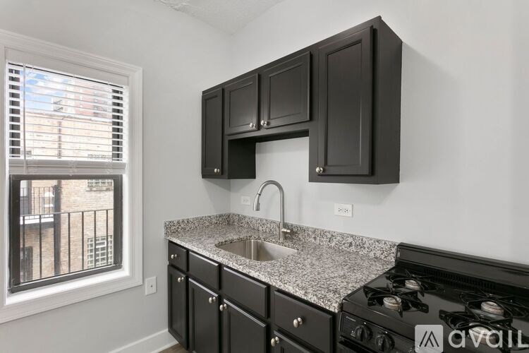 A kitchen with black cabinets and a granite countertop.