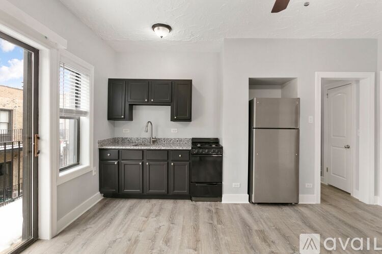 A kitchen with black cabinets and a stainless steel refrigerator.