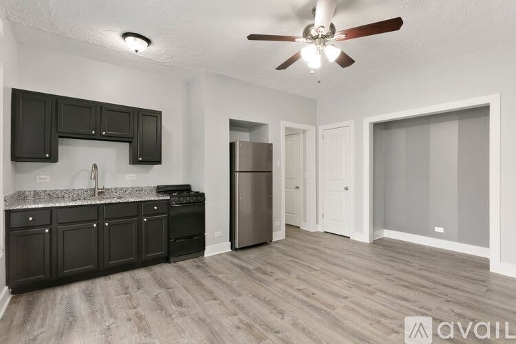 A kitchen with black cabinets and a wooden floor.