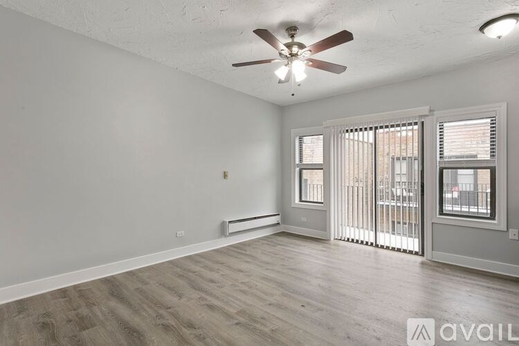 A room with a ceiling fan and sliding glass doors.