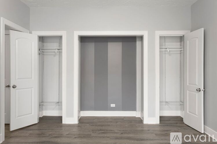 A room with three white doors and a grey wall.
