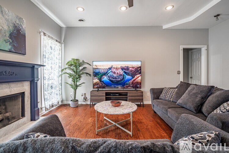 A living room with a grey couch, a fireplace, and a TV playing a movie.