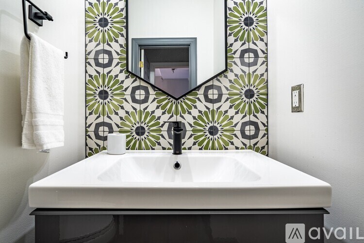 A bathroom sink with a mirror and a green and white tile wall.