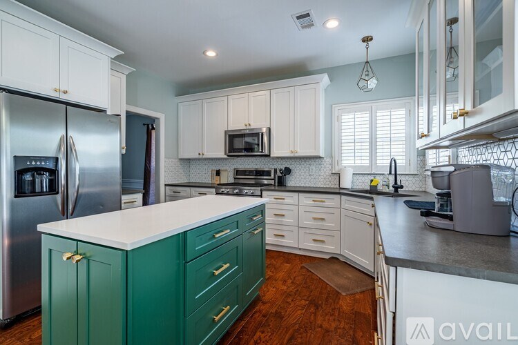 A kitchen with green cabinets and a stainless steel refrigerator.