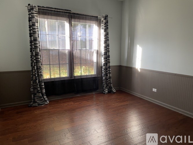 A room with a window covered by a black and white curtain.