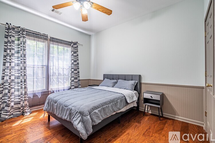 A bedroom with a bed, a ceiling fan, and a window with curtains.