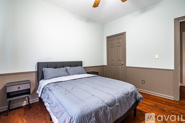 A bedroom with a bed, nightstand, and a ceiling fan.