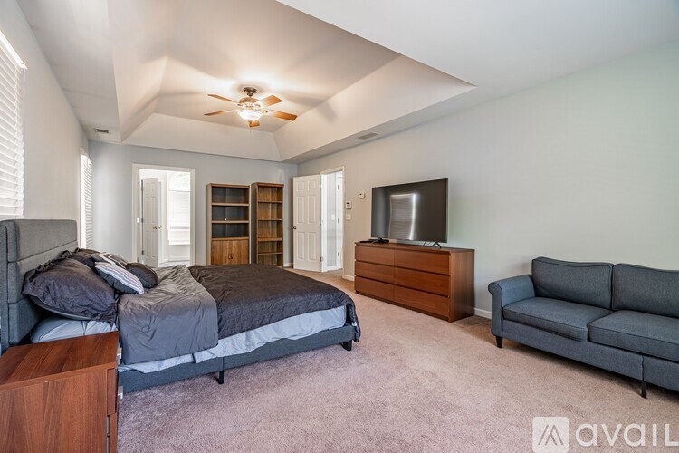 A bedroom with a bed, a couch, and a television.