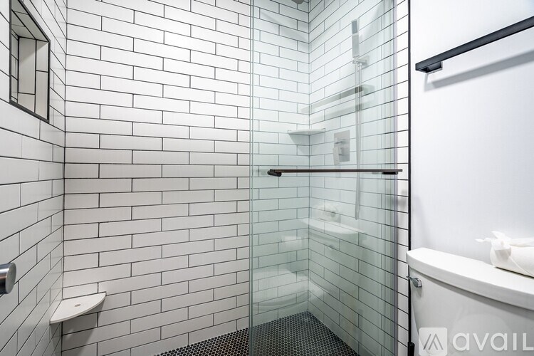 A white tiled bathroom with a glass shower door.