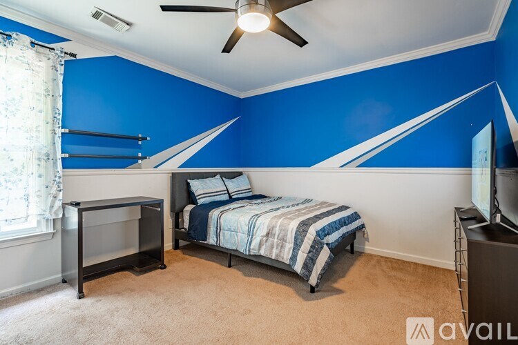 A bedroom with blue walls and a bed with a striped blanket.