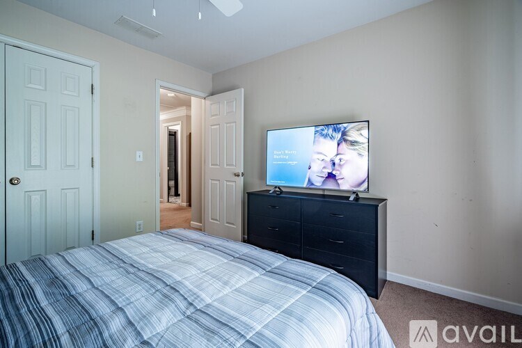 A bedroom with a bed, dresser, and television.