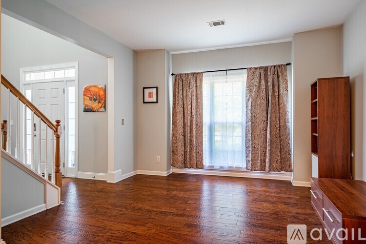 A living room with wood floors and a staircase on the left.